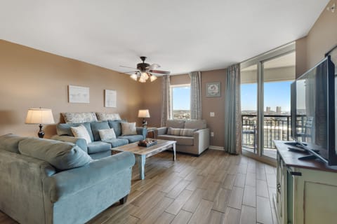 Sink into plush blue sofas while city views unfold through floor-to-ceiling windows in your bright, airy living space.