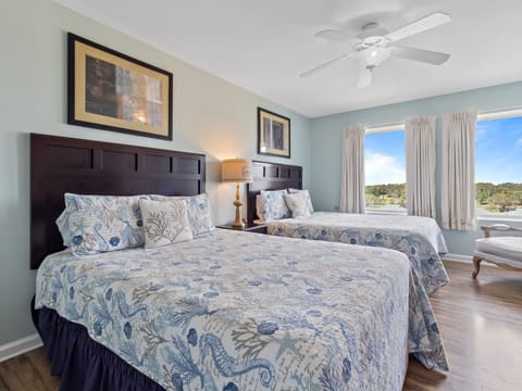 Rest peacefully in this serene twin bedroom featuring coastal-inspired linens and scenic views through large windows.