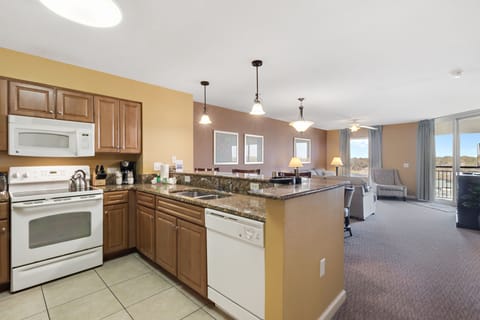 Your spacious open-concept suite features a fully equipped kitchen with granite counters flowing into a comfortable living area with mountain views.