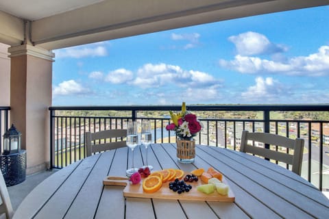 Savor your morning fruit platter on this stunning high-rise balcony, where sweeping city views stretch to the horizon beneath fluffy clouds.