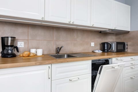 A modern kitchen counter featuring a kettle and microwave. The clean design emphasizes practicality and style.