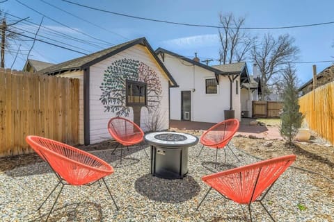 Bright fenced courtyard with bold red chairs circling a round table—grab a drink, settle into the gravel patio, and linger outdoors with friends in view of the cottage.