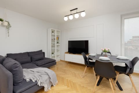 A spacious living room featuring a gray sofa, a modern coffee table, and a dining area in the background.