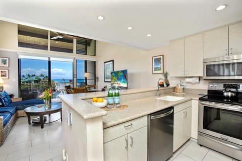 This open kitchen features a spacious island, full-size fridge, and clean cabinetry for effortless island-style living    