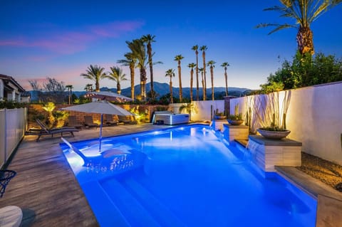 Stunning backyard pool glowing at night w/ palms & ambient lighting for evening swims