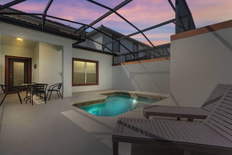 Step outside to your private oasis, featuring a refreshing plunge pool surrounded by sleek loungers and a cozy dining set. The modern, screened enclosure invites you to enjoy the tranquility of the evening sky in complete comfort.