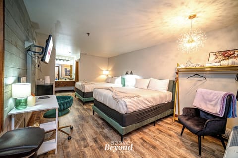 Main sleeping area with two queen beds, television, bathroom, desk, chair, and adorable decor to make you feel right at home on your vacation!