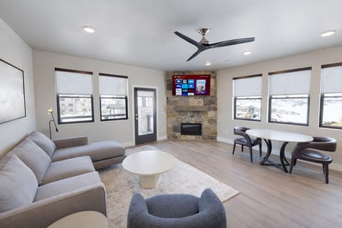Relax in this airy, modern living room featuring a cozy stone fireplace and large windows with mountain views. The open layout and stylish furnishings make it the perfect spot for relaxing after a day of adventure.