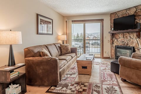 Relax in this open-concept living room featuring a warm fireplace and convenient patio access for fresh mountain air.