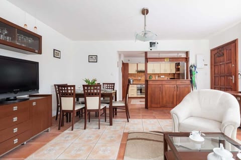 A dining table set up for meals, surrounded by wooden chairs and adjacent to a living room area.