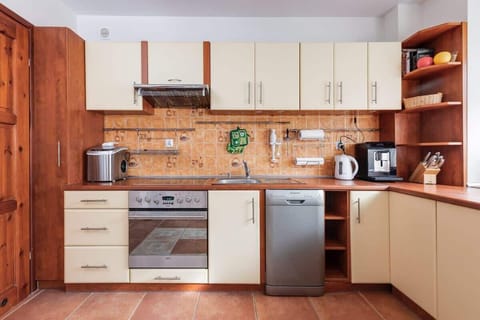 A spacious kitchen with wooden cabinets, modern appliances, and a tiled floor.