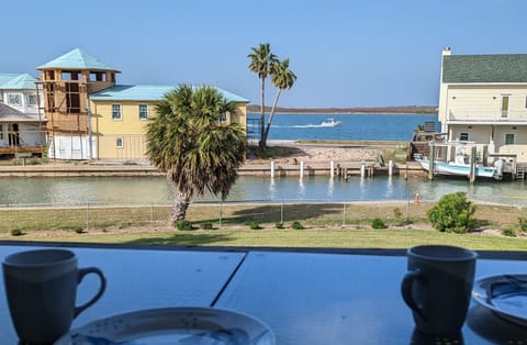 Waterfront views across the canal with colorful coastal homes and palm trees visible from the property's dining area.