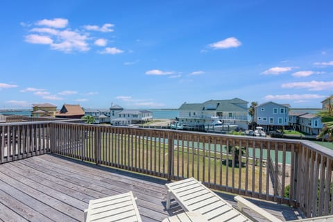 Spacious deck with comfortable seating overlooks coastal homes and bright blue skies, perfect for morning coffee or evening relaxation.