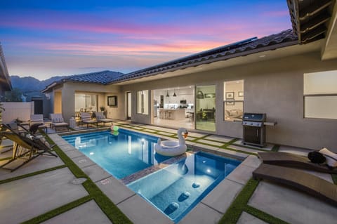 Unwind poolside at dusk w/ glowing lights, spa corner & cozy outdoor lounge seating