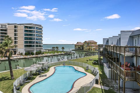 Waterfront resort complex featuring swimming pool, marina docks, and coastal accommodations under clear blue skies.