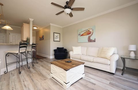 Relax on your plush white sofa with coastal artwork creating a serene atmosphere in your open-concept living space.