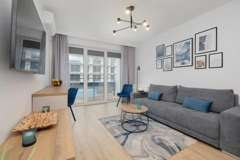 A modern living room with a grey sofa, a wooden coffee table, and framed artwork, creating a cozy and elegant atmosphere.

