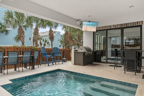 Your private oasis awaits with a sparkling pool, built-in grill, and covered patio framed by swaying palms. Perfect for relaxing or entertaining under the coastal sun.