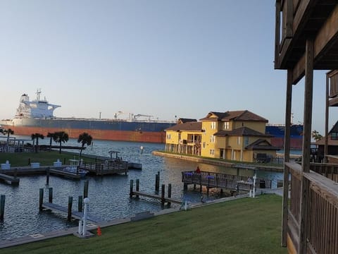 Waterfront property overlooks canal with colorful houses, private docks, and passing tanker ships in this coastal community.