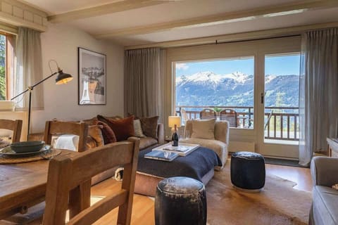 Alpine Elegance
A cozy chalet living room in image_dd212b.png blending warm wooden accents, plush seating, and rustic textures. Expansive windows reveal a private balcony that frames a breathtaking, snow-capped mountain panoramic vista.