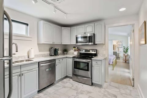 Modern kitchen with stainless appliances, marble-style floors, and coffee setup, opening directly to the bedroom and bath. Convenient, bright, and perfect for cooking between outings in the French Quarter.