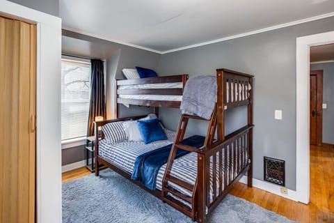 Shared bedroom in Rochester, with wooden bunk bed, striped bedding & cozy accents—efficient retreat blending comfort, style and smart design.