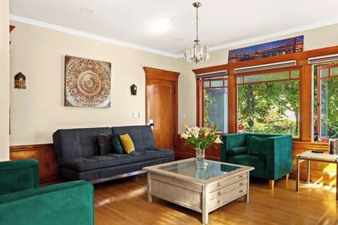 Unwind in this inviting living room featuring rich wood accents, vibrant green chairs, a cozy sofa, and large windows that fill the space with natural light