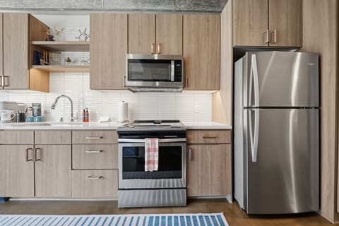 Modern, fully equipped kitchen with stainless steel appliances, ample counter space, and warm wood cabinetry ready for your culinary adventures.