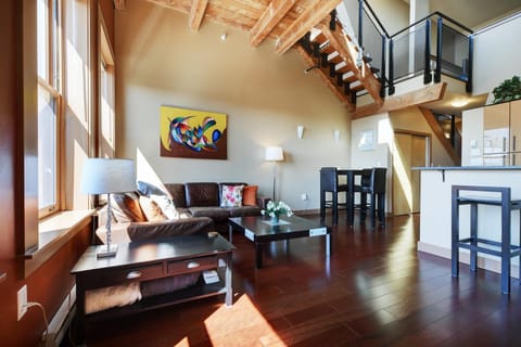 Welcome to loft luxury! Relax in the open-concept living area featuring soaring ceilings and exposed timber details.