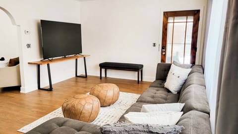 Spacious living room with large TV and foot rests.
