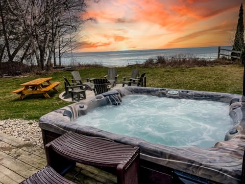 Private hot tub overlooking Lake Michigan with sunset views, fire pit seating, and a spacious waterfront yard in Door County