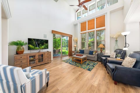 Relax in your bright, airy living room with soaring ceilings, comfortable seating, and tropical garden views through expansive windows.