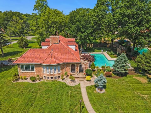 Aerial view of this elegant brick villa set on expansive grounds with a private pool and mature trees. Pool is open seasonally from May 15 through August 31. A rare retreat in North Kansas City.