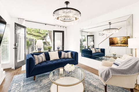 The spacious living room boasts an inviting open-concept design, with a massive Smart TV and comfortable sofa and chair, serving as the focal point for both relaxation and entertainment. French doors lead out to your private patio. 