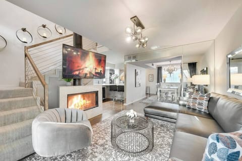 From the living room, enjoy a clear view of the stairs leading to the loft space, complemented by a cozy fireplace and a large smart TV, creating a perfect blend of comfort and style.