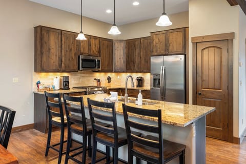 - Modern kitchen with granite counters and wood cabinetry   - Stainless steel appliances including fridge and microwave   - Bar seating with pendant lighting for casual dining moments