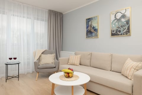 A bright, inviting living area featuring a comfortable beige sofa, a round coffee table, and decorative wall art.