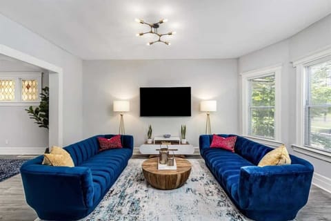 Elegant living room with plush blue sofas and TV.