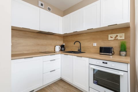 A well-organized kitchen with white cabinetry, a wooden countertop, and modern appliances. The backsplash is kept simple, enhancing the clean aesthetic.