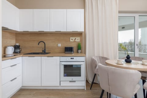A different perspective of the kitchen, showing the built-in appliances, a sink, and a window that allows for natural light. The white and wood combination adds warmth to the space.