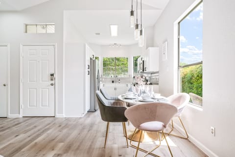 mid-century oval shaped modern dining table set with six grey and blush chairs.