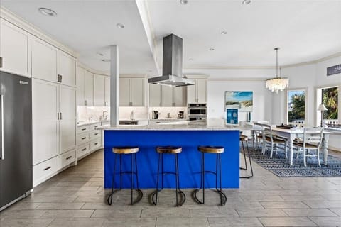 Bright, airy space with a bold blue island and elegant lighting for culinary fun