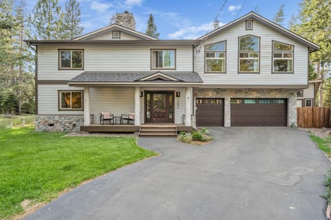 Exterior view of two-story house with stone accents, dark wood garage doors, and a small covered porch with seating.