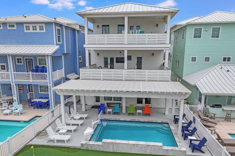 Colorful beach houses surround this modern vacation rental with private pool and spacious outdoor entertaining area in a vibrant coastal neighborhood.