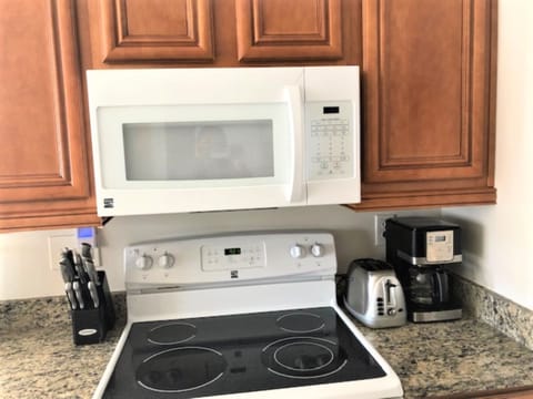 White microwave and stove surrounded by wood cabinetry