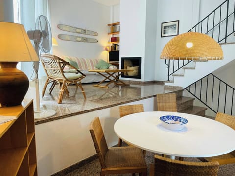 Natural light illuminates the split-level design of this inviting townhouse, highlighting the warm tones of the wicker furniture and polished stone floor.