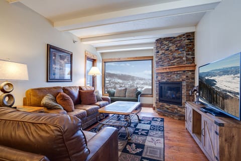 Cozy up by your stone fireplace while enjoying stunning mountain views through expansive windows in this perfectly appointed living room.