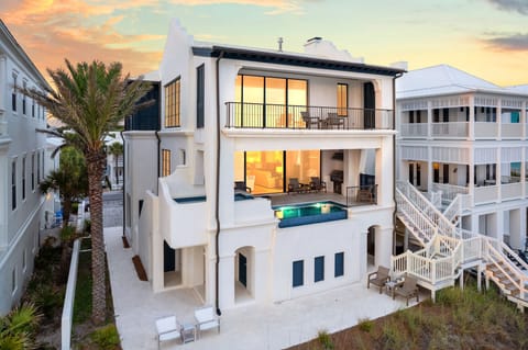 Modern beachside villa with private pool and multiple balconies in an upscale coastal neighborhood during golden hour.