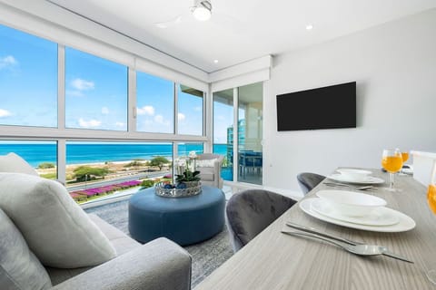 Bask in breathtaking ocean views from your bright, modern living space where plush seating and floor-to-ceiling windows frame the turquoise coastline—your perfect retreat after sun-soaked beach days.