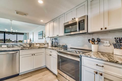 Modern kitchen with breakfast bar and stainless appliances at Wind Drift Orange Beach vacation condo